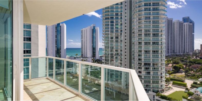 A row of condominium buildings with balconies and a sunset in the background